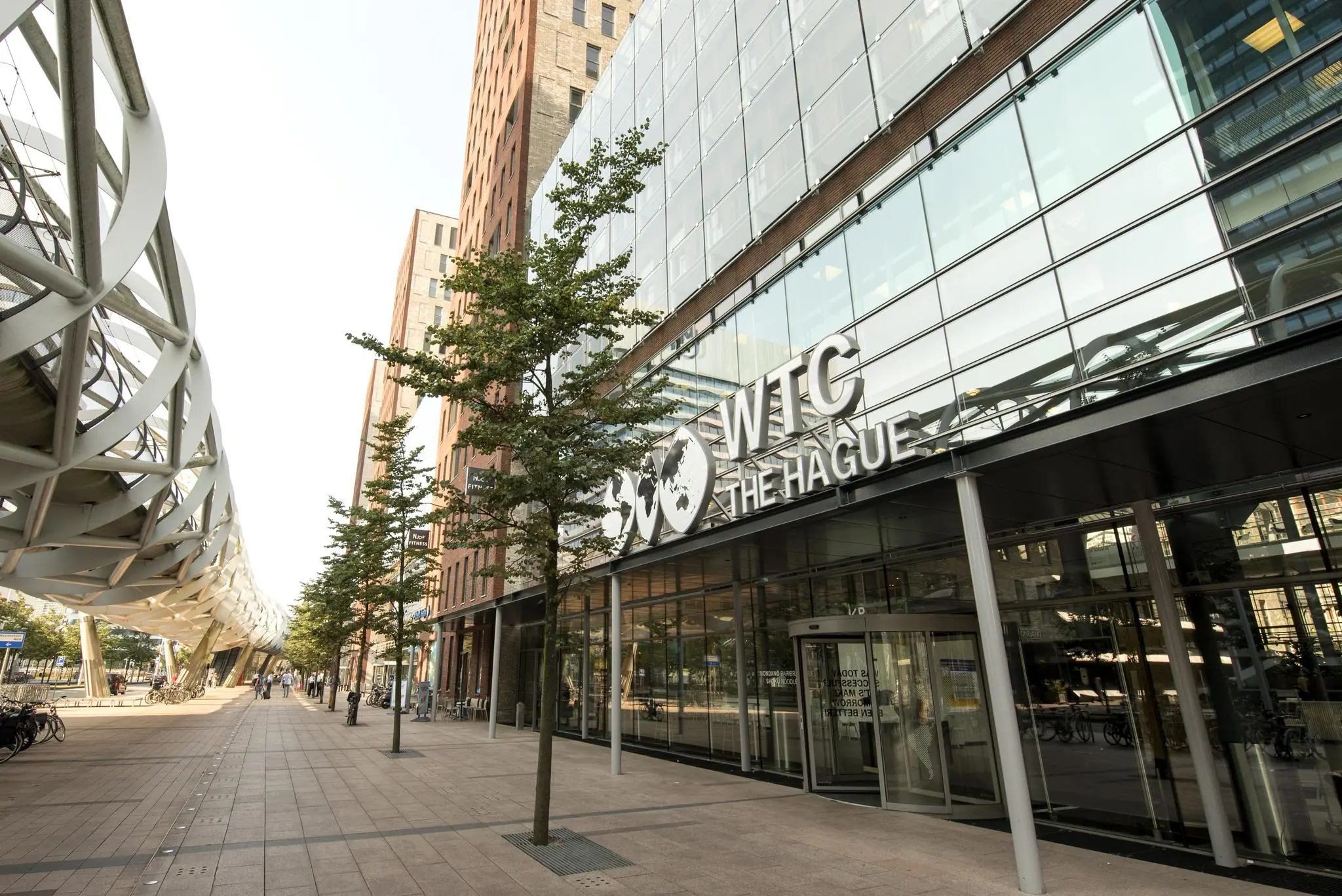 Ingang van het WTC The Hague aan de Prinses Beatrixlaan met moderne gevel en naastgelegen wandelpromenade.